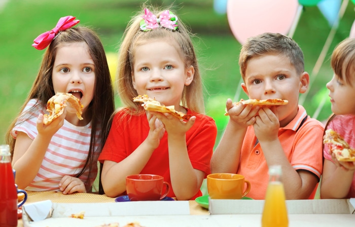 four children eating pizza at a pizza party